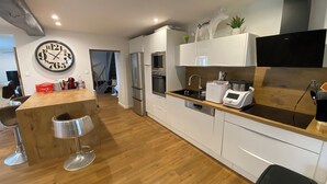 Una cocina moderna con armarios blancos, encimera de madera, electrodomésticos de acero inoxidable y un reloj en la pared.