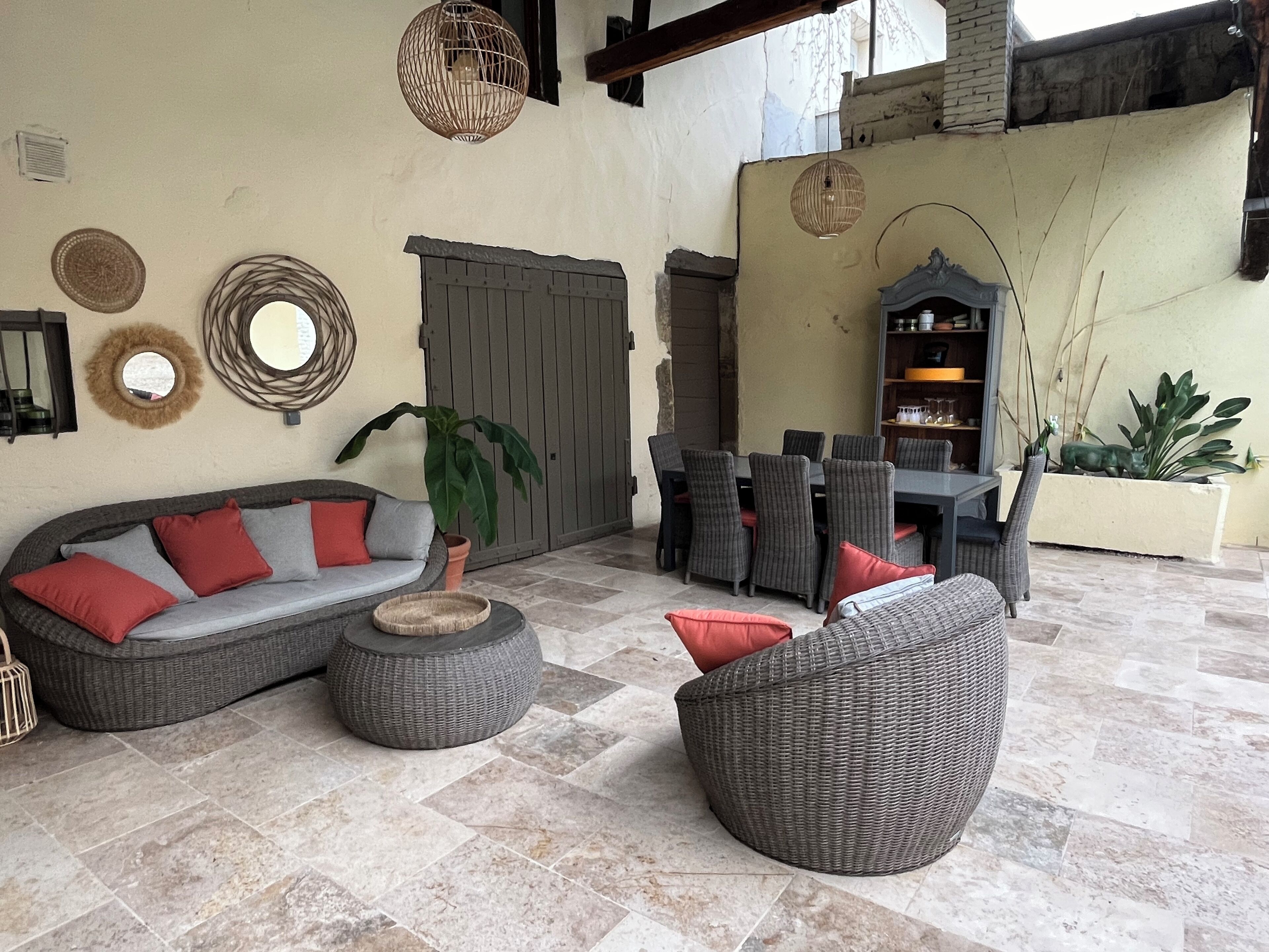 A spacious outdoor seating area with a sofa, chairs, and a round table.