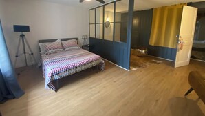 Un dormitorio con cama, ventilador de techo, lámpara de trípode y puerta corrediza que da a otra habitación.