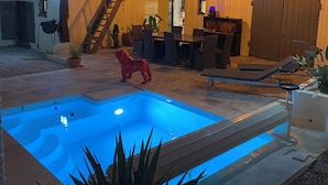 Zona de piscina con jacuzzi, sillas de descanso y una escalera que lleva a un nivel superior.