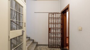 Ένα στενό κλιμακοστάσιο με μεταλλική πόρτα και ξύλινη πόρτα στην κορυφή.