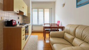 Ένας μικρός, λειτουργικός χώρος διαβίωσης με μικρή κουζίνα, τραπεζαρία και καναπέ.