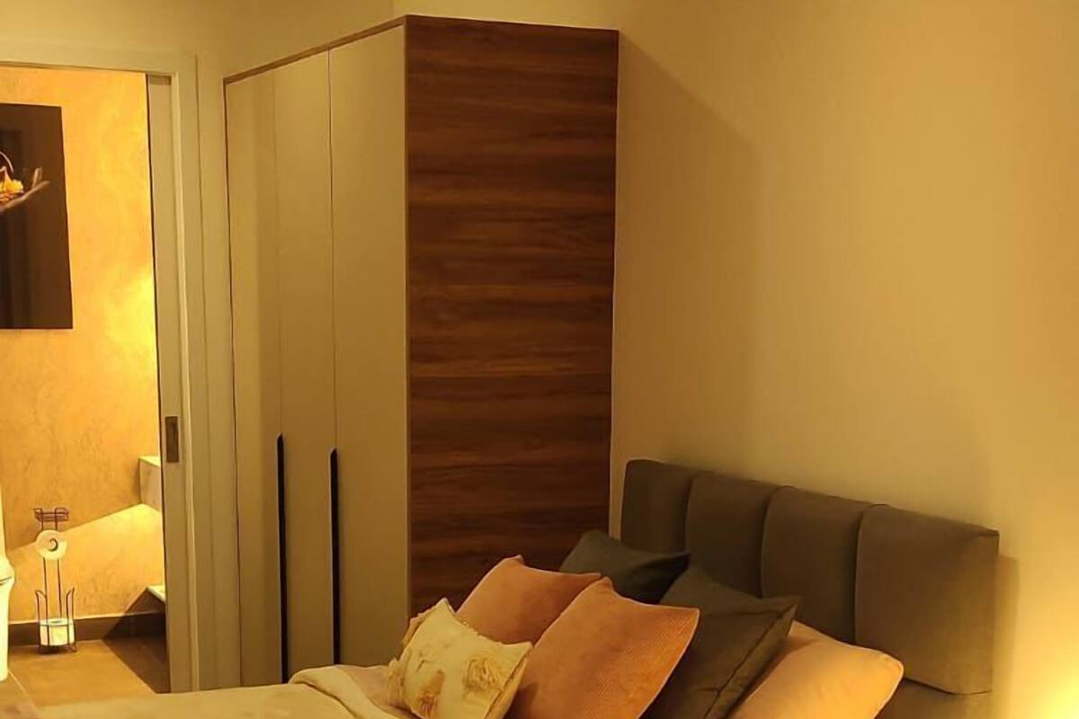 A modern bedroom with a bed, bedside table, and a wardrobe.