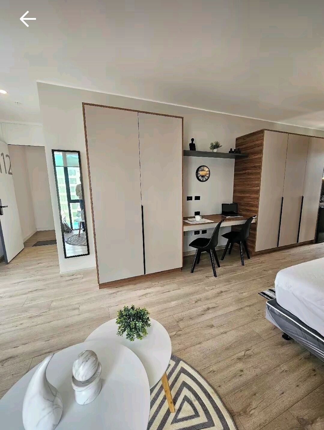 Ein modernes Hotelzimmer mit einem großen Bett, einem Schreibtisch mit Stuhl und einem Kleiderschrank.