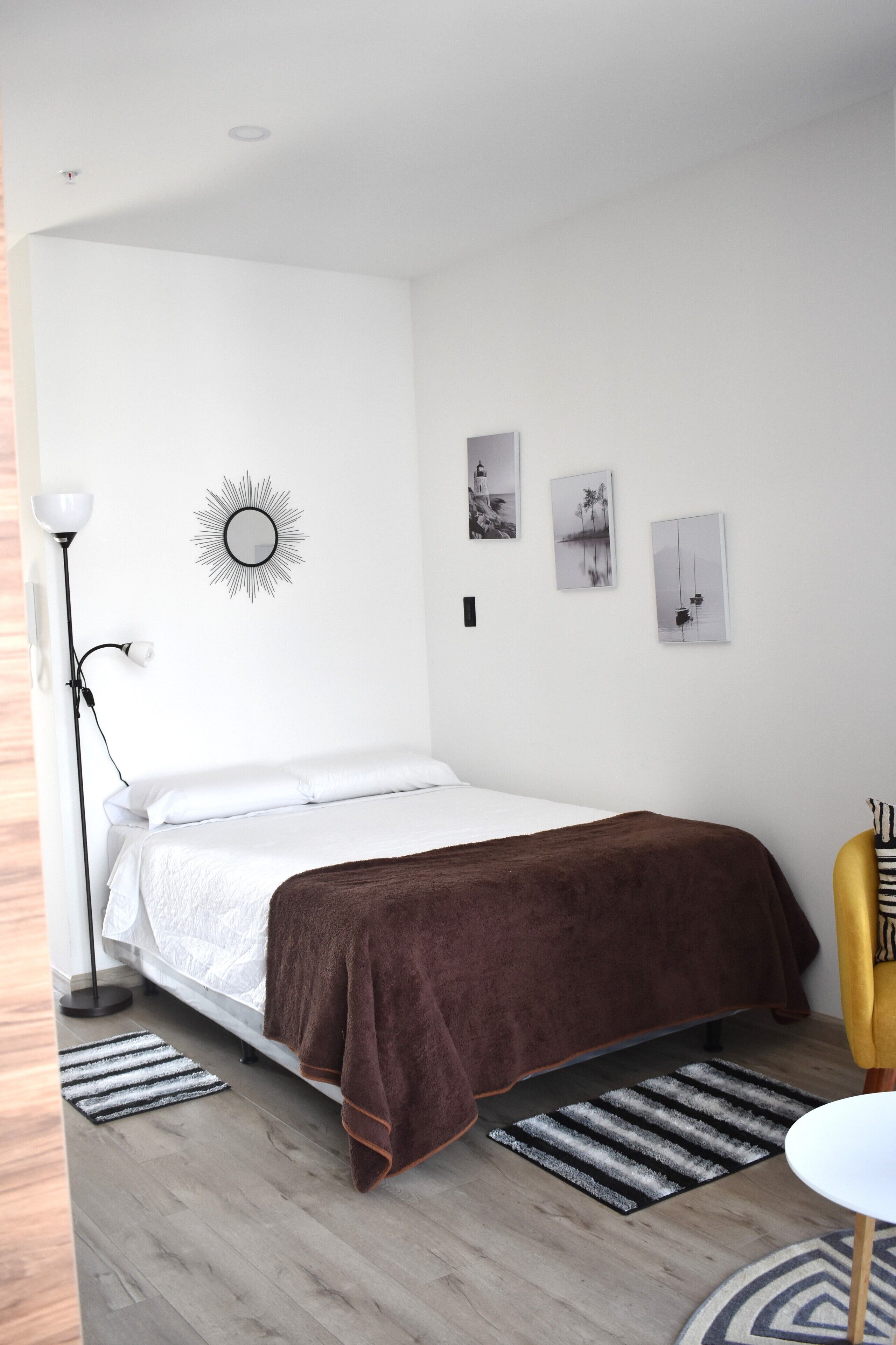 Ein Schlafzimmer mit einem Bett, einer Stehlampe, einem Spiegel und Bildern an der Wand.