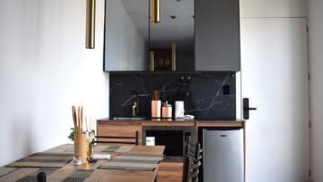 Uma cozinha moderna com painel de parede de mármore, eletrodomésticos de aço inoxidável e uma mesa de jantar de madeira com jogos americanos.