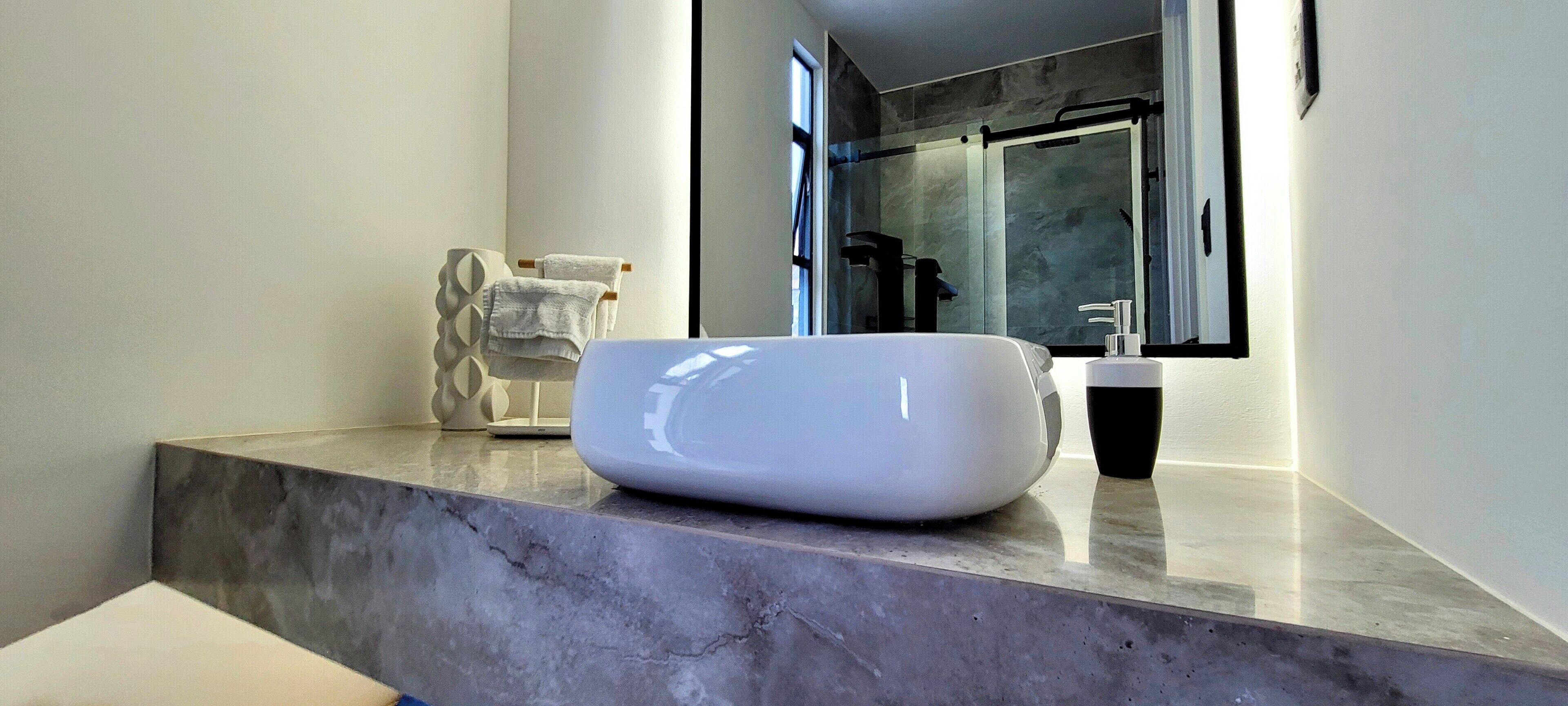 Une salle de bain moderne avec un comptoir en marbre, un lavabo blanc et un porte-serviettes.