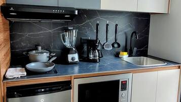 Eine moderne Küche mit Geschirrspüler, Herd, Mikrowelle und Mixer auf der Arbeitsfläche.