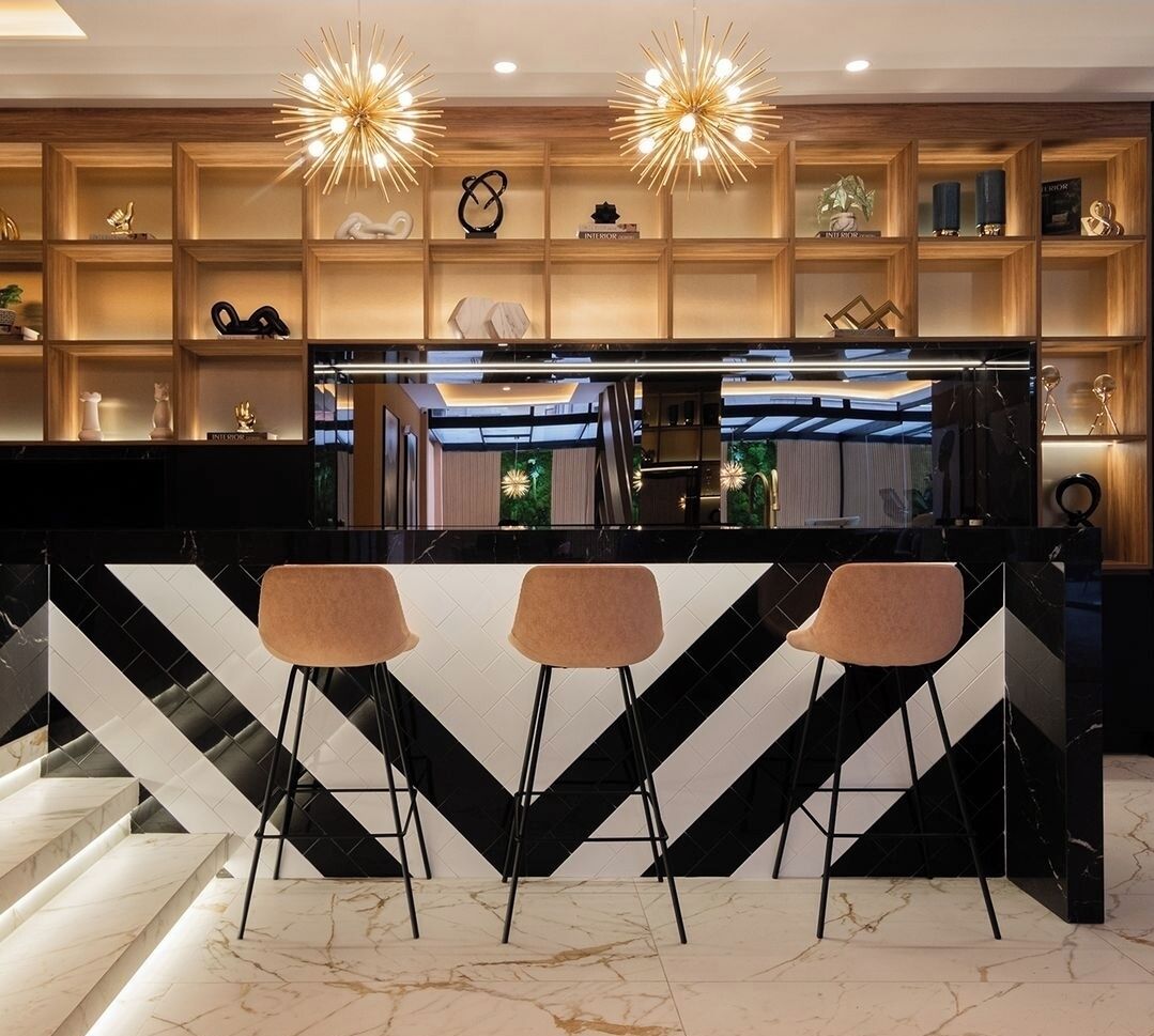 Cozinha moderna com painel de mármore preto e branco, três banquetas e luminárias pendentes.