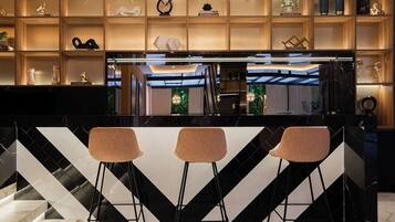 Cozinha moderna com painel de mármore preto e branco, três banquetas e luminárias pendentes.