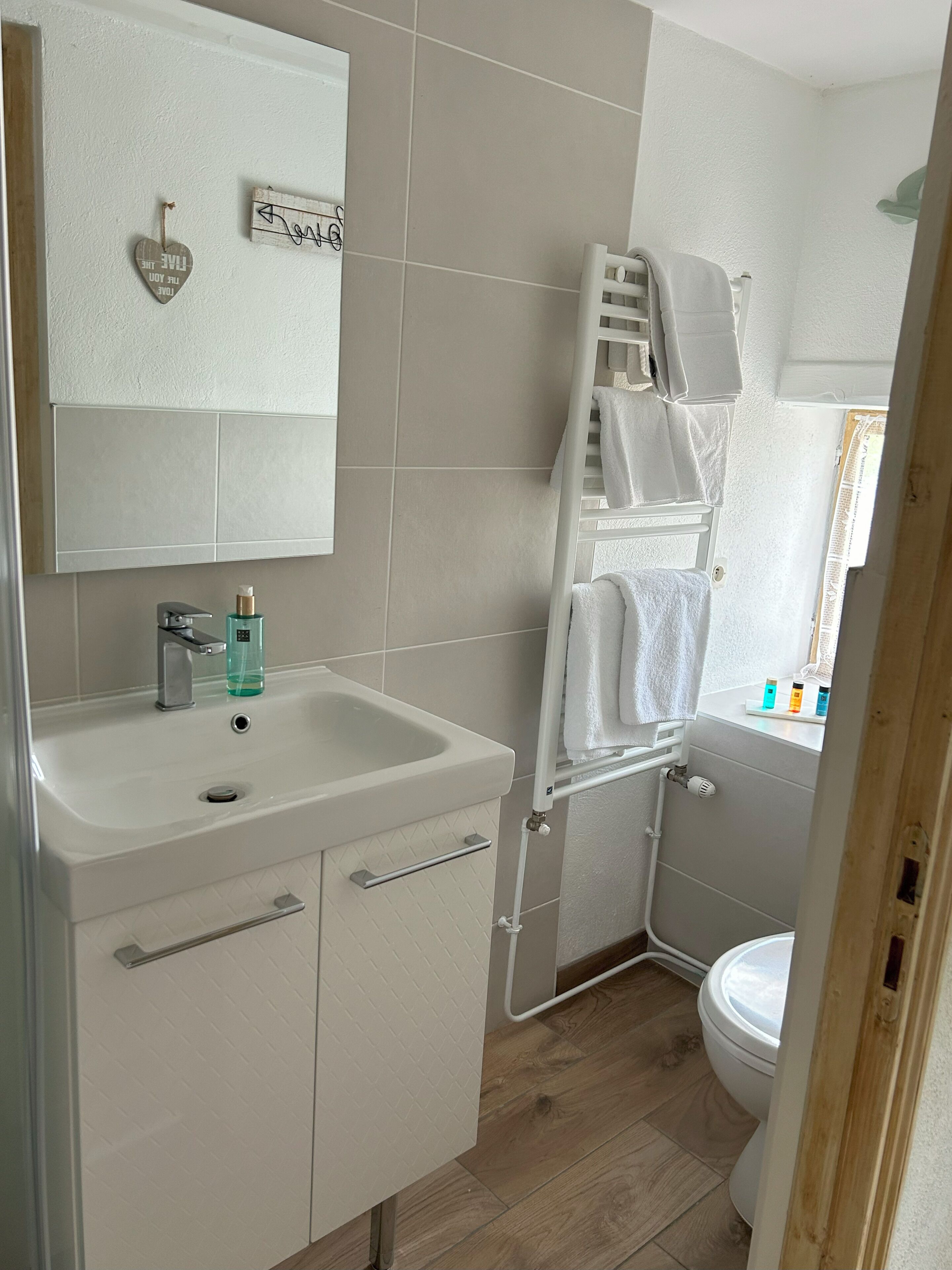 Un baño con un lavamanos blanco, un espejo, un perchero para toallas y un inodoro.
