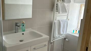 Un baño con un lavamanos blanco, un espejo, un perchero para toallas y un inodoro.