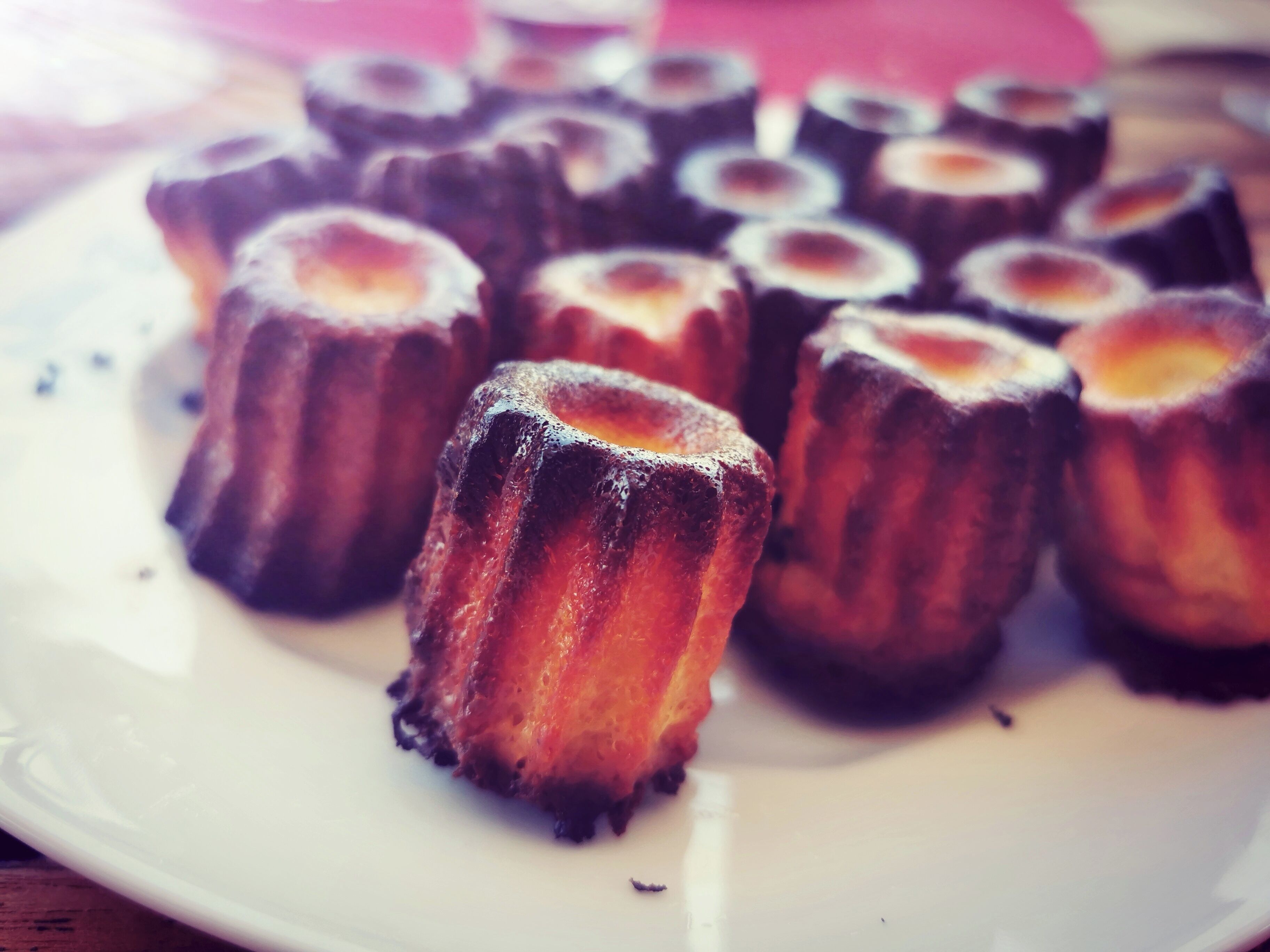 A plate of canelés, a type of French pastry, arranged on a white plate.