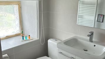 A compact bathroom with a toilet, sink, and window.