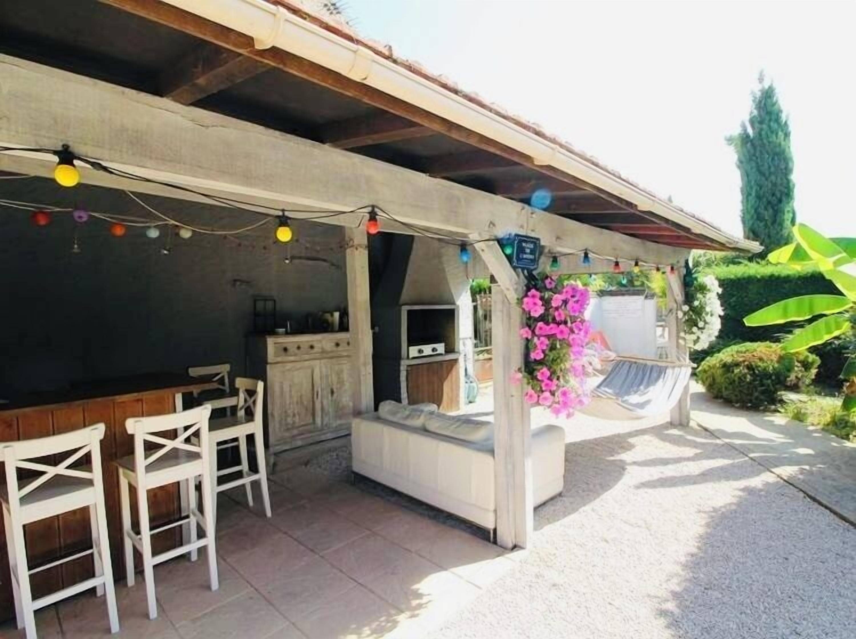 An outdoor patio with a dining area, a sofa, and a hanging flower arrangement.