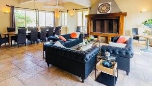 Amplia sala de estar con chimenea, asientos cómodos y comedor.