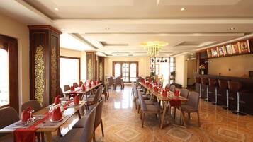 A spacious dining area with long tables, chairs, and a bar counter.