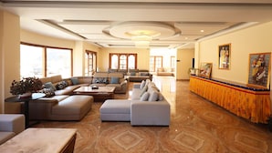 A spacious living area with a large sofa set, a coffee table, and a decorative plant. - Paro Grand Resort (Paro)