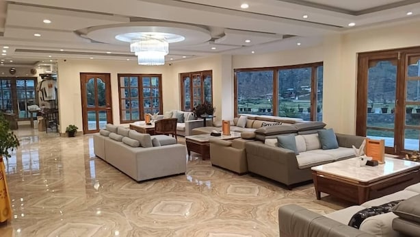 A spacious living area with large windows, a chandelier, and a modern interior design. - Paro Grand Resort (Paro)