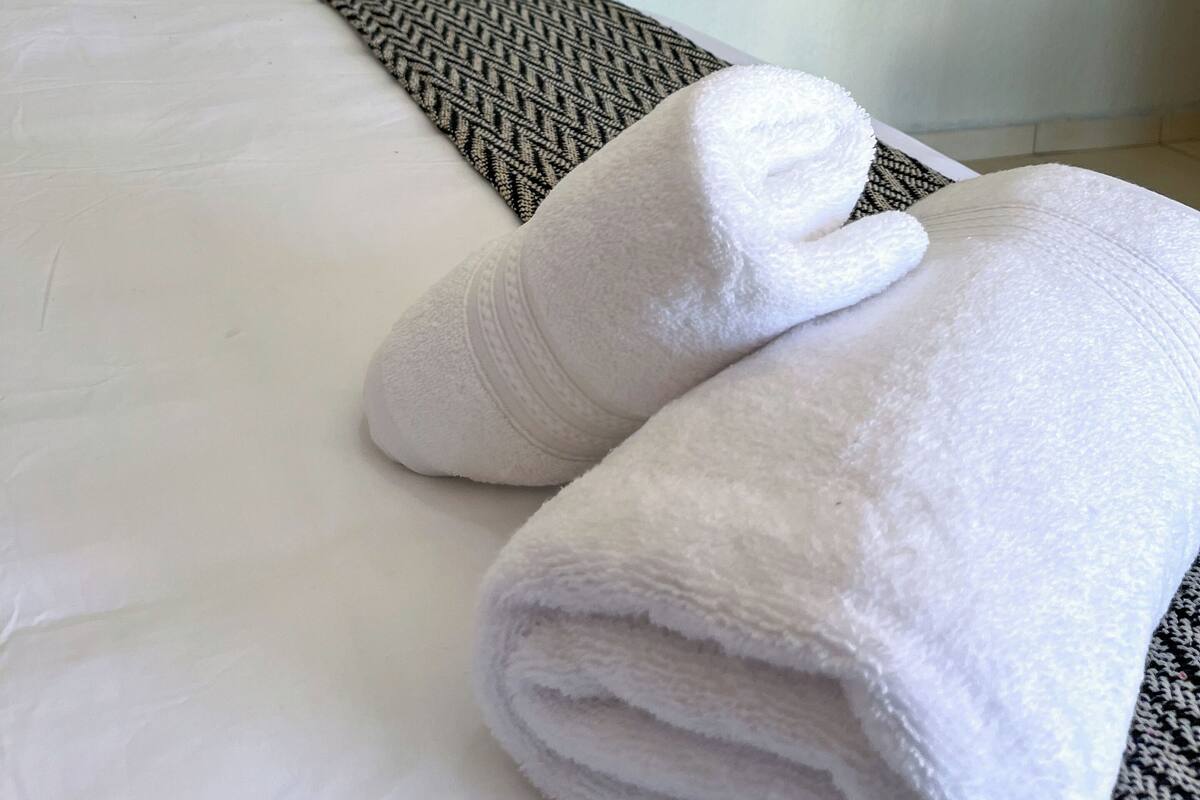 A neatly made bed with white linens and a patterned throw blanket.