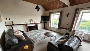 Un salon chaleureux avec une cheminée, des canapés en cuir et un téléviseur.