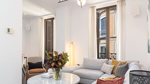 En moderne stue med en grå sofa, et rundt sofabord og en vase med blomster.