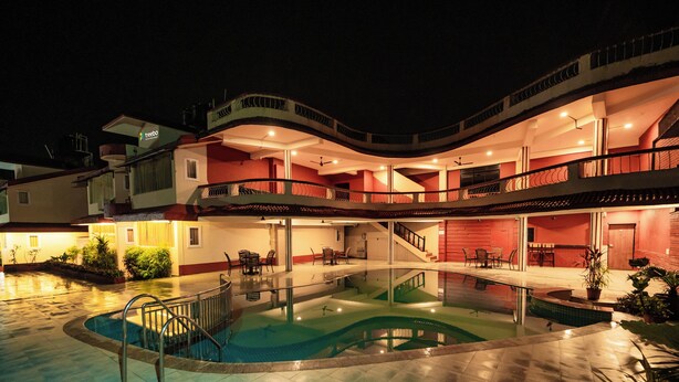 Et hotel med flere etager, swimmingpool, udendørs siddepladser og en trappe, der forbinder etagerne.