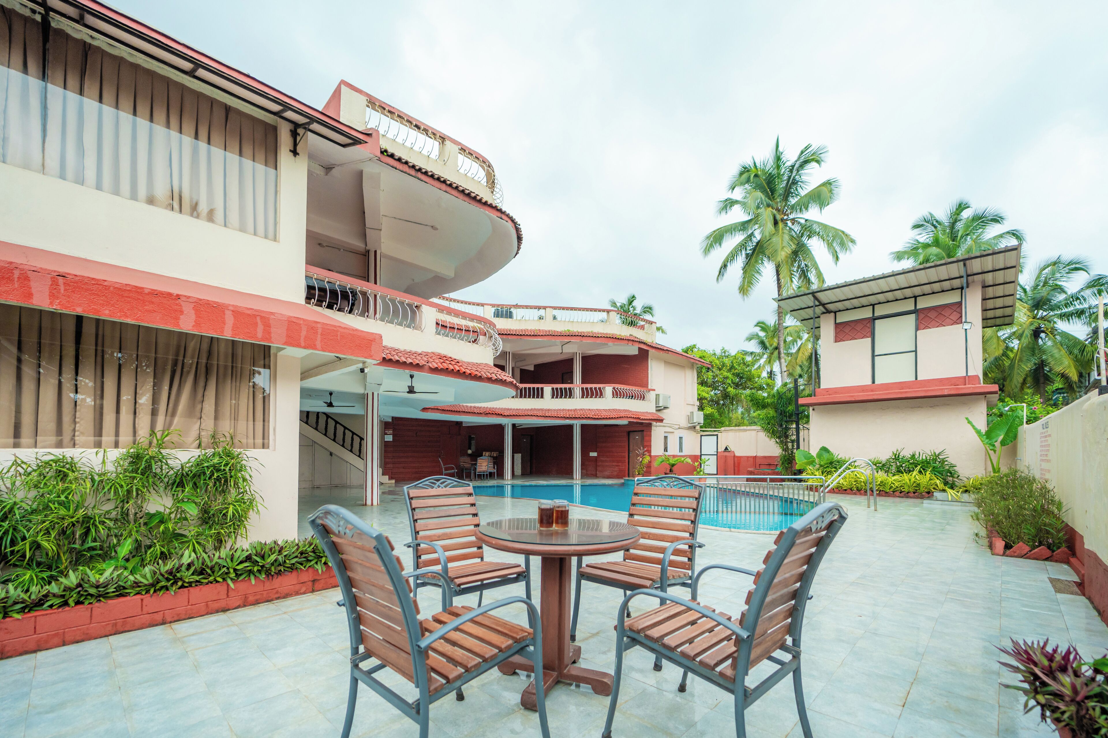 A hotel with a pool, outdoor seating, and a two-story building with balconies.