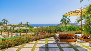 Une terrasse avec vue sur l’océan, des sièges d’extérieur et une variété de plantes.