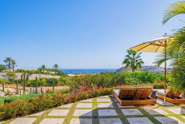 Une terrasse avec vue sur l’océan, des sièges d’extérieur et une variété de plantes.