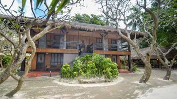 A building with a thatched roof, surrounded by trees and greenery.