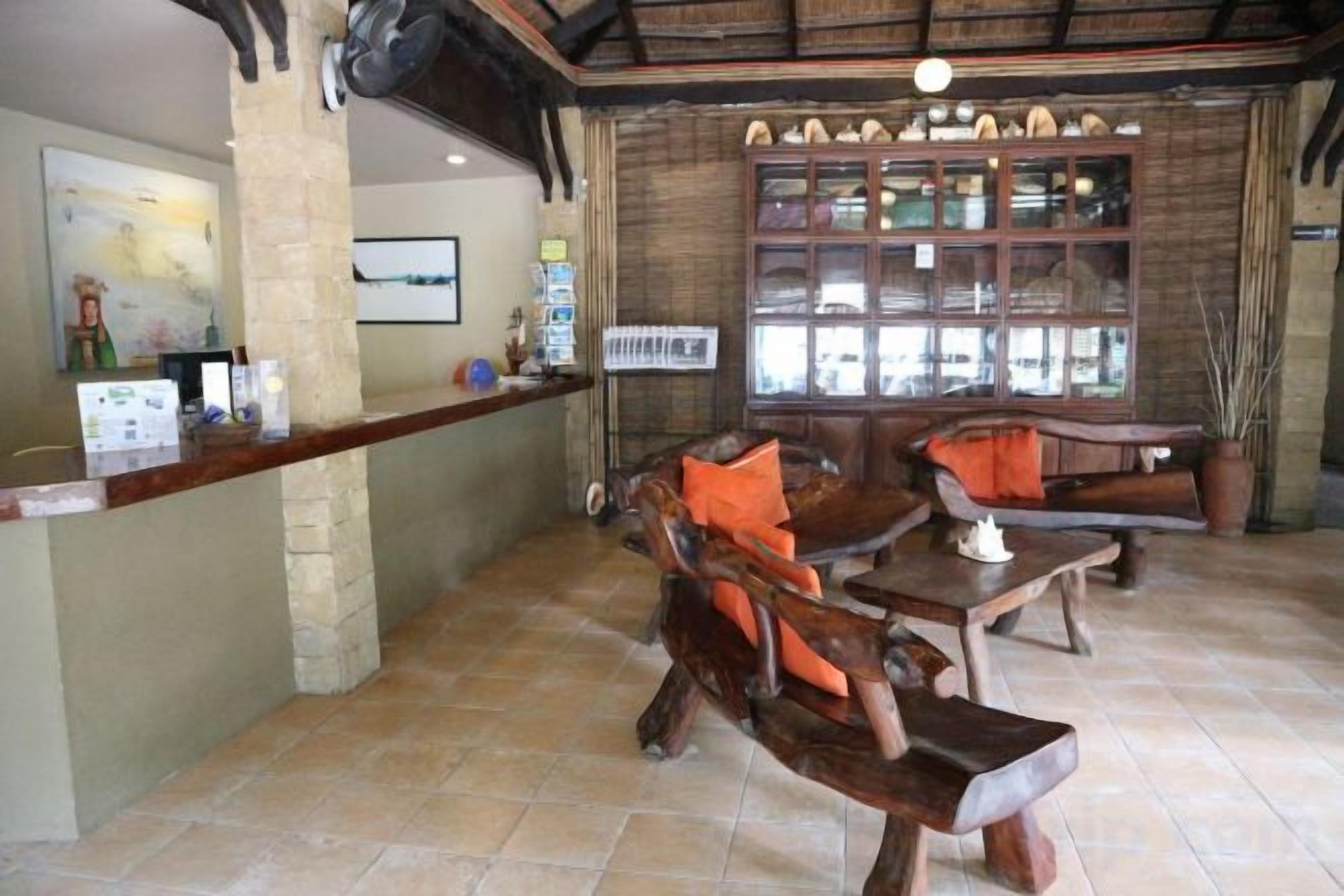 A rustic interior with a wooden bar counter, seating area with wooden furniture, and a large window with multiple panes.