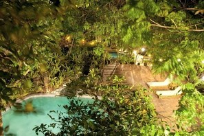 A pool area surrounded by dense foliage, with lounge chairs and a stone deck. - Sea Wind Resort (Boracay Island)