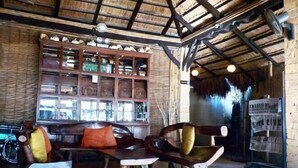 A rustic interior with wooden furniture, a brick wall, and a thatched roof. - Sea Wind Resort (Boracay Island)
