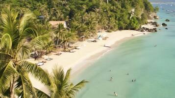 A beach with clear turquoise water, palm trees, and a sandy shore.