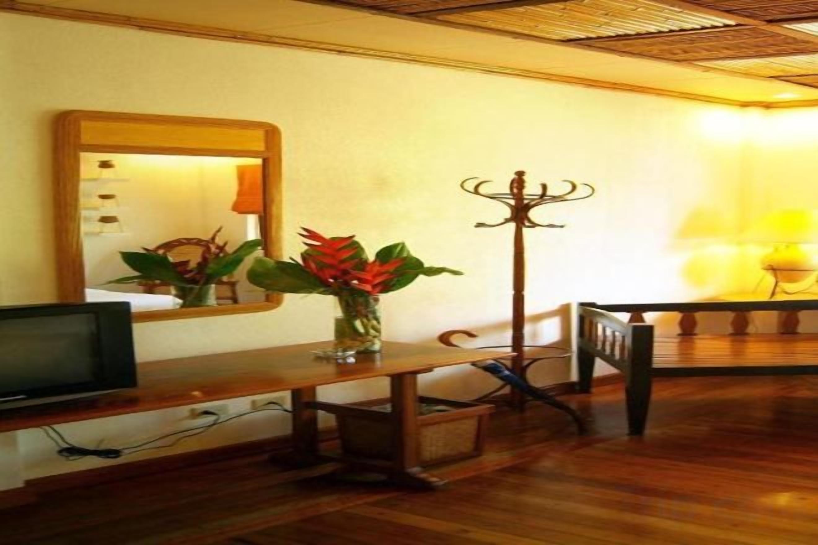 A wooden bench, a television, and a mirror in a room with a wooden floor.