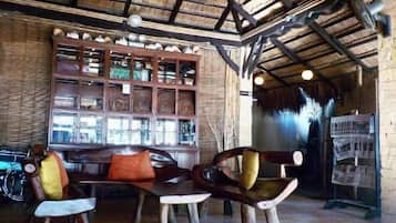 A rustic interior with a wooden ceiling, a wooden bench with cushions, and a display cabinet.