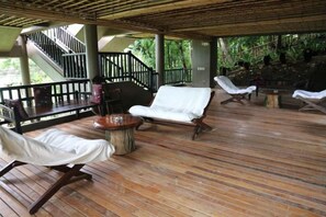 A covered outdoor area with wooden flooring, lounge chairs, and a staircase. - Sea Wind Resort (Boracay Island)