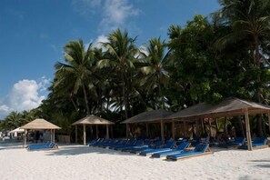 Una playa con tumbonas y palmeras.