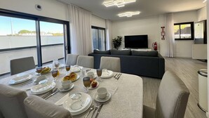 A modern hotel room with a dining area, a sofa, a flat-screen TV, and a balcony with a view. - FARO PRESTIGE by HOMING (Faro)