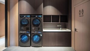 Un espace buanderie compact comprenant deux machines à laver à chargement frontal superposées et un évier.