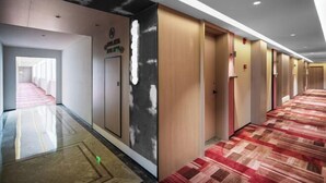 Un couloir d’hôtel avec un tapis à motifs, des portes en bois et un panneau indiquant l’emplacement d’une salle de sport.