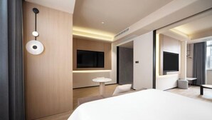 Une chambre d’hôtel moderne avec un grand lit, une télévision, une petite table ronde et un canapé.