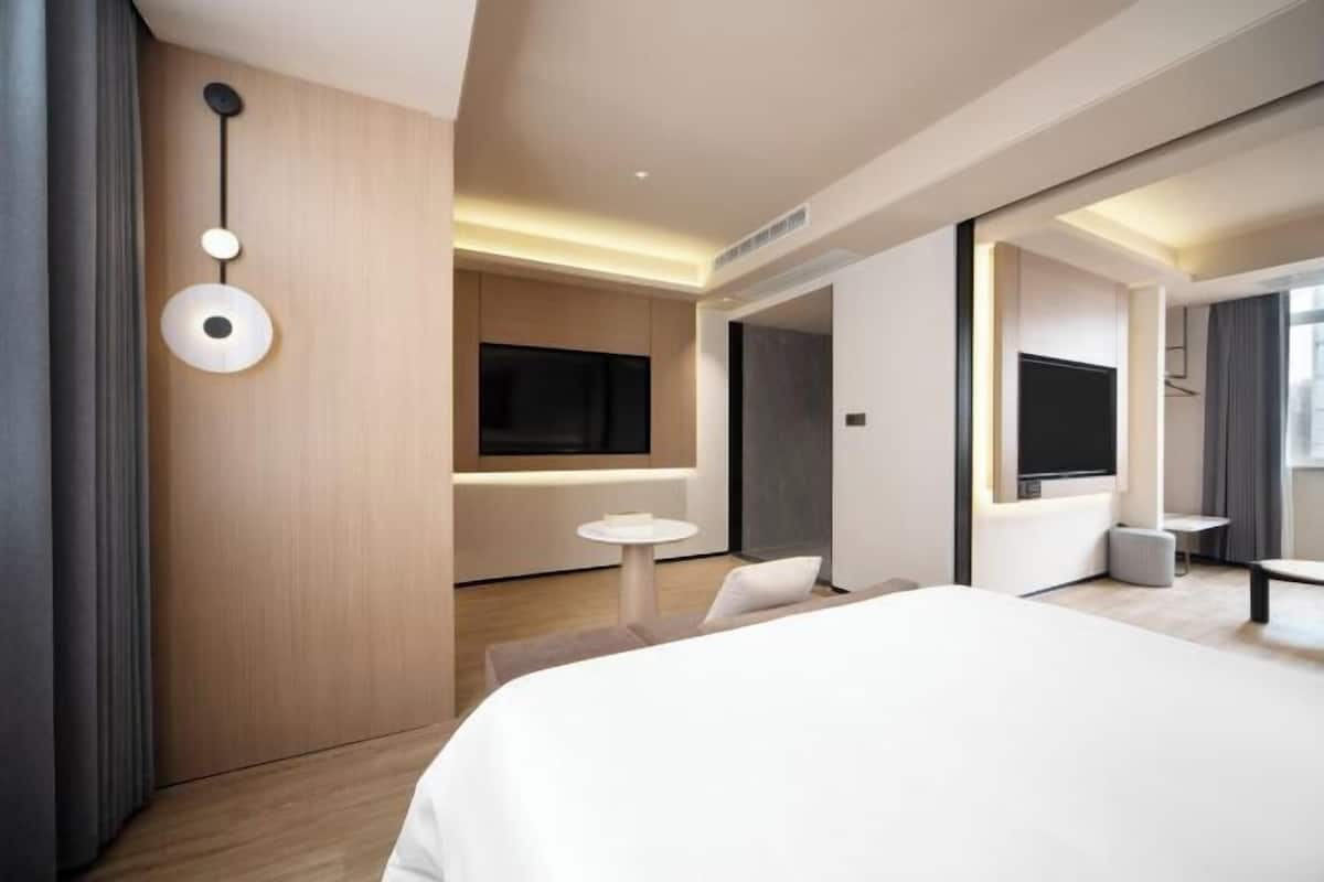Ein modernes Hotelzimmer mit einem großen Bett, einem Fernseher, einem kleinen runden Tisch und einer Couch.