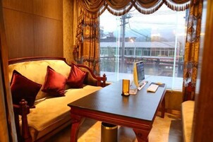 Una habitación con sofá, una mesa y vistas a un edificio desde la ventana.