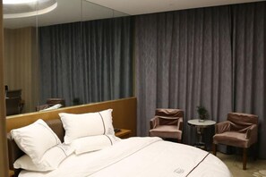 A hotel room with a large bed, a small round table, two chairs, and a mirror. - Zhicheng Boyue Boutique Hotel (Ningqiang)