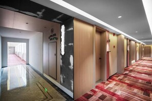 Un pasillo de hotel con piso alfombrado, puertas y un cartel con el nombre del hotel.