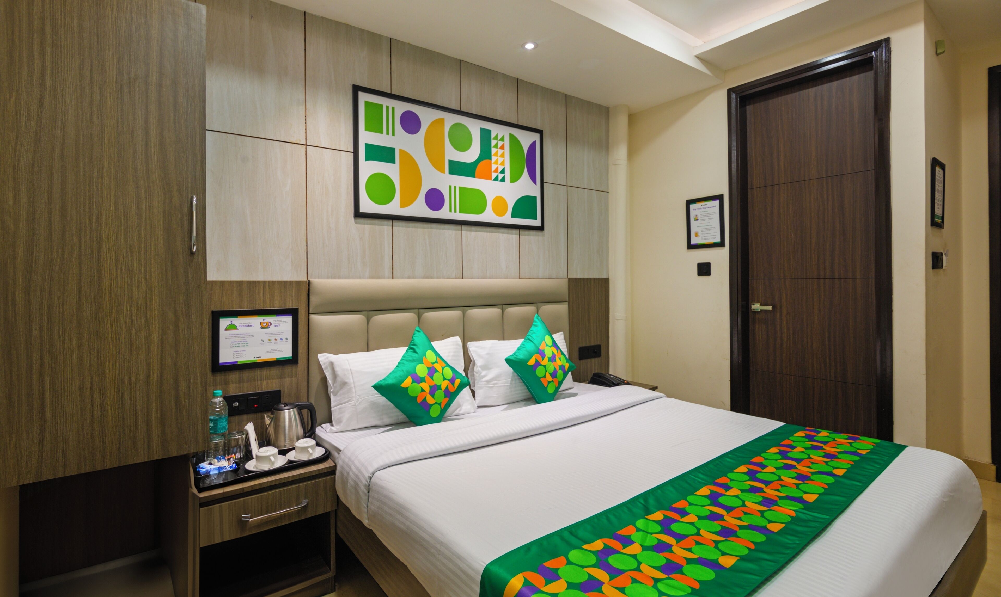 A hotel room with a bed, a nightstand, a coffee maker, and a framed menu on the wall.
