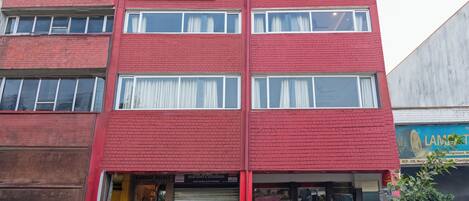 A red-brick building with a sign for 'Treebo' and 'Bombay Palace' hotel.