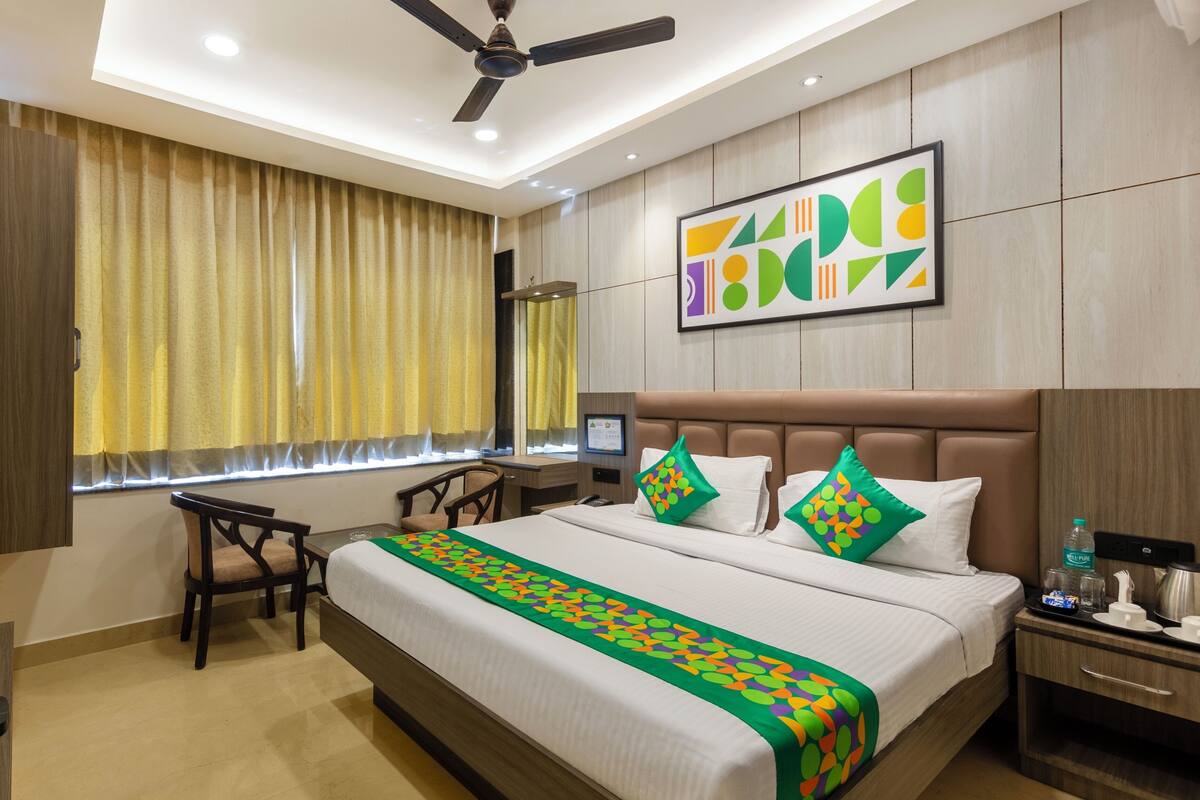 A hotel room with a bed, a desk, a chair, a television, and a ceiling fan.